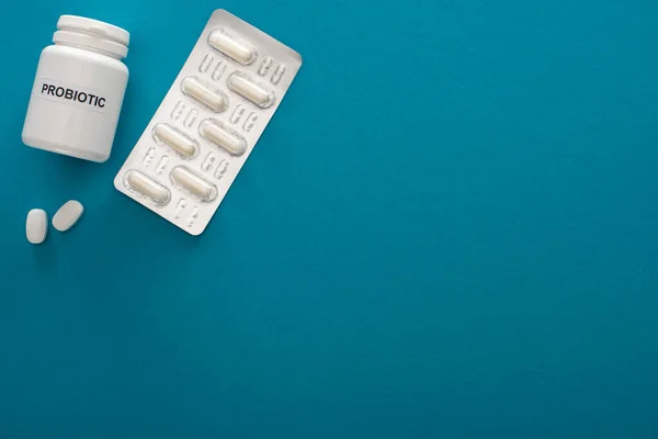 Top view of container with probiotic lettering, pills and blister pack on blue background — Stock Photo