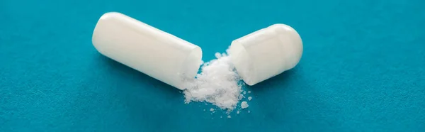 Close up view of probiotic capsule with white powder on blue background, panoramic shot — Stock Photo