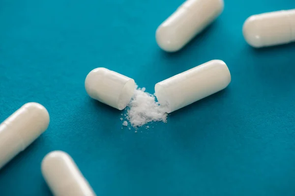 Nahaufnahme probiotischer Kapseln mit weißem Pulver auf blauem Hintergrund — Stockfoto