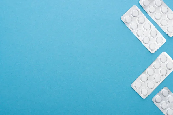 Вид таблеток в блистерных упаковках на синем фоне — стоковое фото
