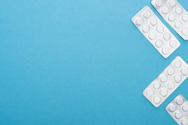 Top view of pills in blister packs on blue background — Stock Photo