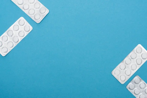 Vista superior de pílulas em embalagens blister no fundo azul — Fotografia de Stock