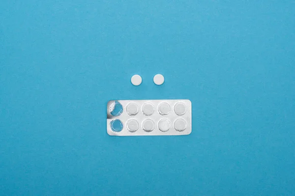 Vista superior da pílula e embalagem blister no fundo azul — Fotografia de Stock