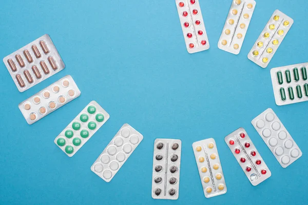 Vista superior de pílulas coloridas em embalagens blister no fundo azul — Fotografia de Stock