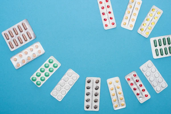 Draufsicht auf bunte Pillen in Blisterverpackungen auf blauem Hintergrund — Stockfoto