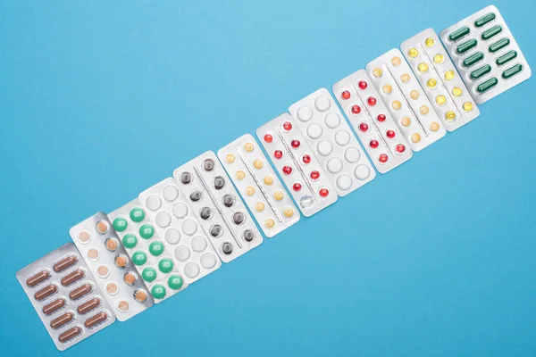 Top view of colorful pills in blister packs on blue background — Stock Photo