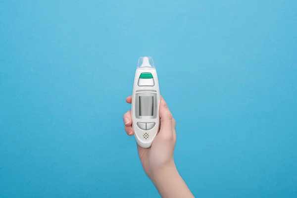 Cropped view of woman holding ear thermometer on blue background — Stock Photo