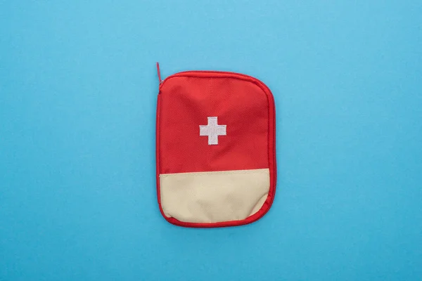 Vue du dessus de la trousse de premiers soins rouge sur fond bleu — Photo de stock