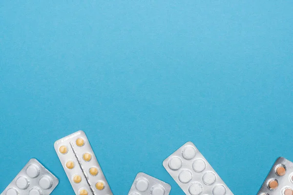 Top view of pills in blister packs on blue background — Stock Photo