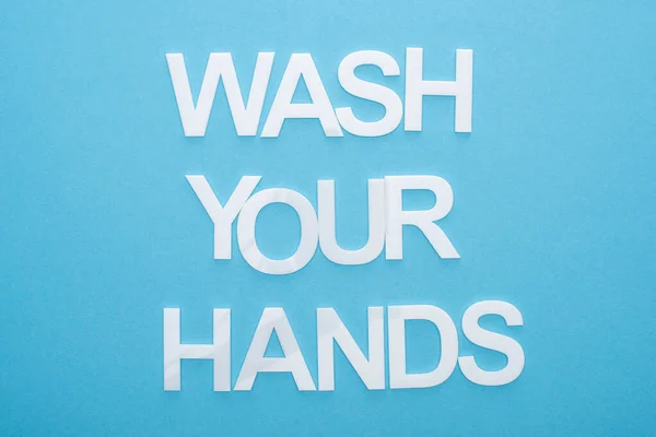 Vista superior de lavarse las manos con letras sobre fondo azul - foto de stock