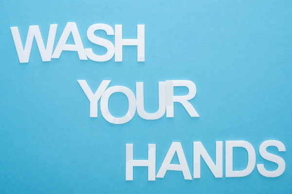 Vista superior de lavarse las manos con letras sobre fondo azul - foto de stock