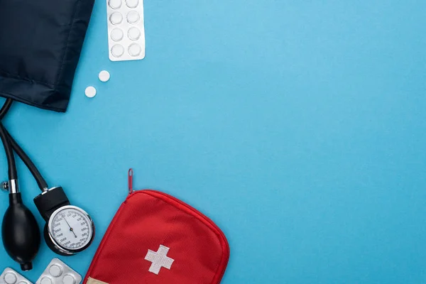 Ansicht von Pillen in Blisterverpackungen, Blutdruckmessgerät, Verbandskasten auf blauem Hintergrund — Stockfoto