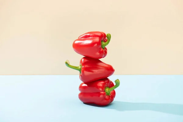 Fresh red bell peppers on blue surface isolated on beige — Stock Photo