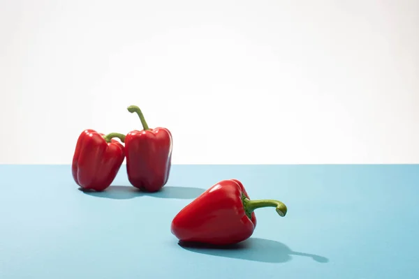 Fresh red bell peppers on blue surface on white background — Stock Photo