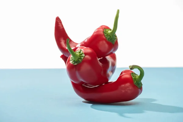 Fresh red chili peppers on blue surface isolated on white — Stock Photo
