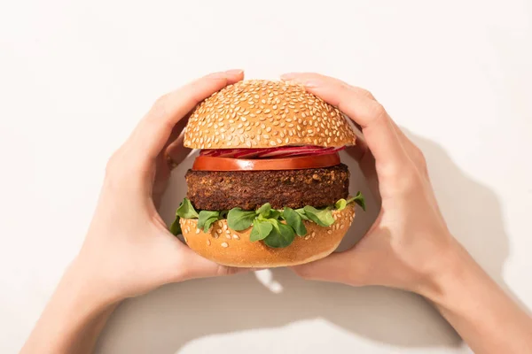 Cropped view of woman holding delicious vegan burger with radish on white background — Stock Photo