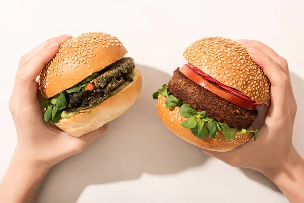 Cropped view of woman holding delicious vegan burgers on white background — Stock Photo