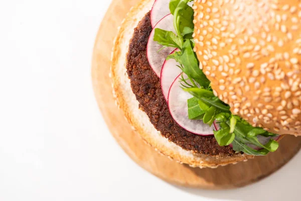 Draufsicht auf leckeren veganen Burger mit Rettich und Rucola auf Holzbrett auf weißem Hintergrund — Stockfoto