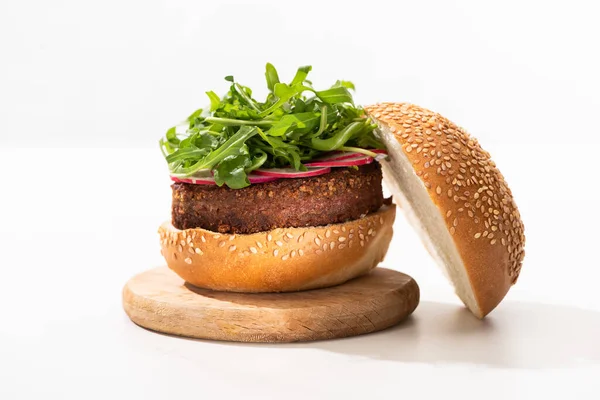 Leckere vegane Burger mit Rettich und Rucola auf Holzbrett auf weißem Hintergrund — Stockfoto