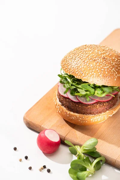 Leckere vegane Burger mit Rettich und Rucola auf Holzbrett mit schwarzem Pfeffer auf weißem Hintergrund — Stockfoto
