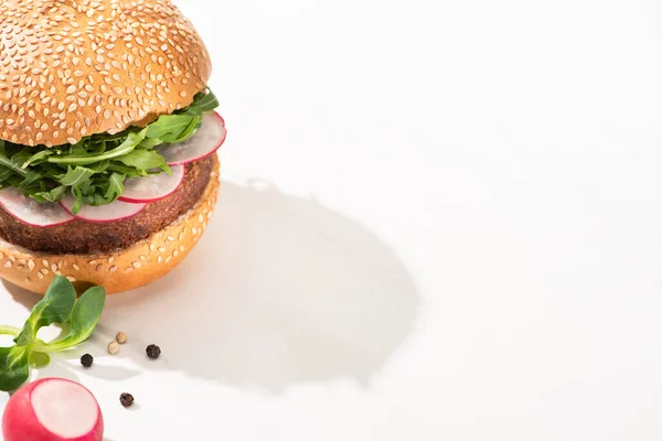 Deliciosa hamburguesa vegana con rábano y rúcula con pimienta negra sobre fondo blanco - foto de stock
