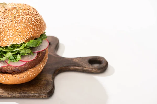 Hamburger végétalien délicieux avec radis et roquette sur planche de bois sur fond blanc — Photo de stock