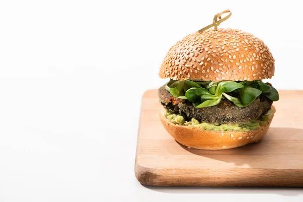 Delicious green vegan burger with microgreens and mashed avocado on wooden boar on white background — Stock Photo