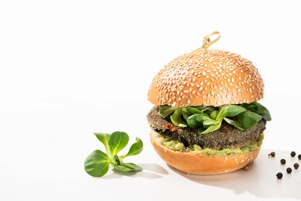 Вкусный зеленый веганский бургер с микрозеленью, черный перец на белом фоне — стоковое фото