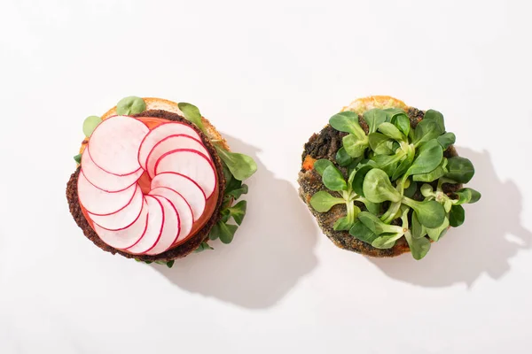 Vista superior de hamburguesas veganas con microgreens, rábano sobre fondo blanco - foto de stock