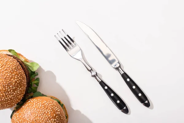 Top view of vegan burgers near fork and knife on white background — Stock Photo