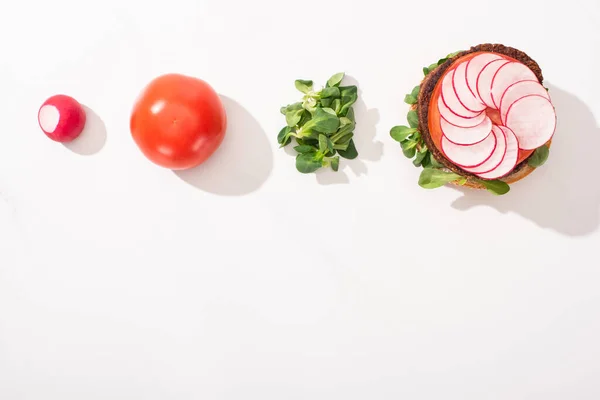 Vista dall'alto di hamburger vegan con ravanello, pomodoro e germogli su sfondo bianco — Foto stock