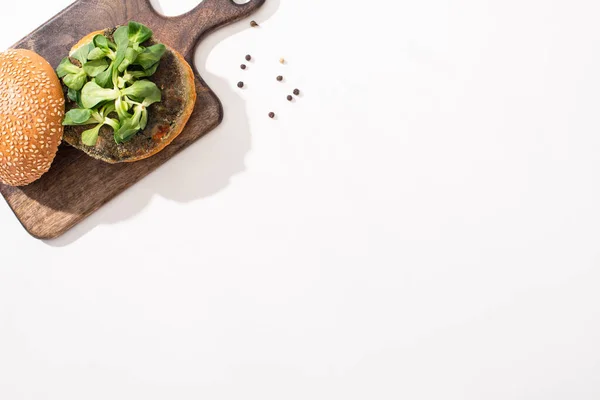 Вид на веганский бургер с микрозеленью на деревянной доске на белом фоне — стоковое фото