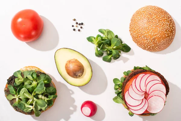 Ansicht von veganen Burgern mit Zutaten auf weißem Hintergrund — Stockfoto