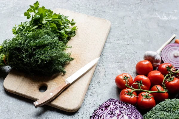 Légumes mûrs frais colorés près de la planche à découper avec couteau sur la surface en béton gris — Photo de stock