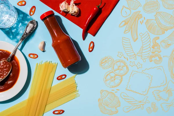 Top view of spicy ketchup with garlic and chili pepper beside spaghetti on blue background, food illustration — Stock Photo