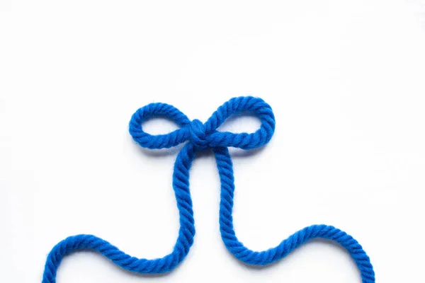 Top view of bow made of blue wool yarn on white background — Stock Photo