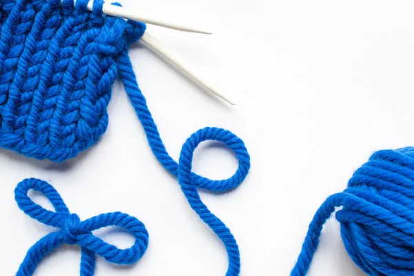 Fil de laine bleue et aiguilles à tricoter sur fond blanc — Photo de stock