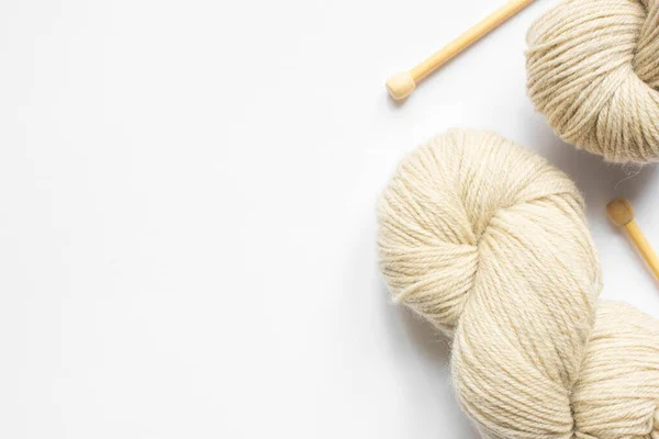 Beige yarn and knitting needles on white background with copy space — Stock Photo