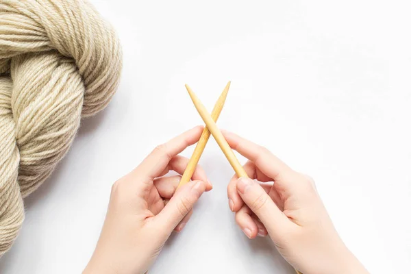 Vista superior de las manos femeninas con hilo beige y agujas de punto sobre fondo blanco — Stock Photo