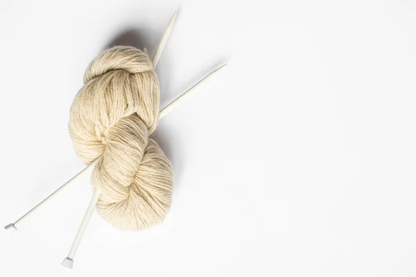 Top view of beige yarn and knitting needles on white background with copy space — Stock Photo