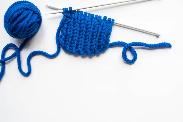 Vue du dessus des fils de laine bleue et des aiguilles à tricoter sur fond blanc — Photo de stock