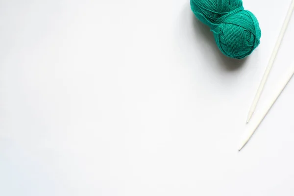 Vue du dessus des fils de laine verte et des aiguilles à tricoter sur fond blanc — Photo de stock