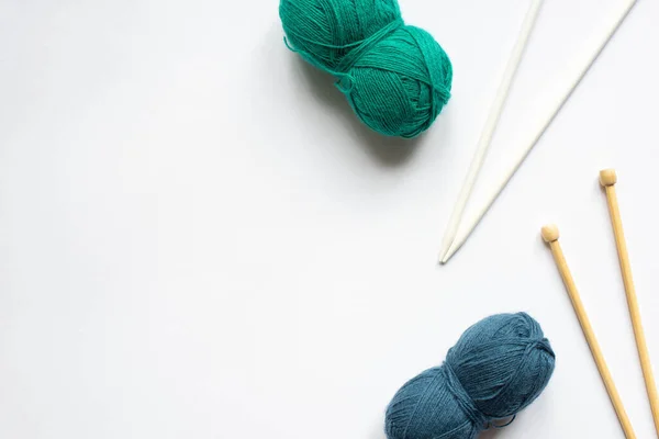 Top view of blue and green wool yarn and knitting needles on white background — Stock Photo