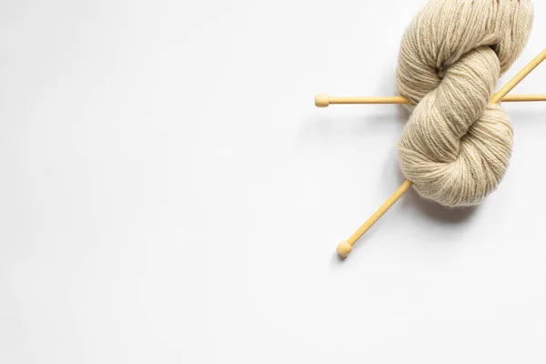 Vista dall'alto di filati di lana beige e ferri da maglia su sfondo bianco — Foto stock