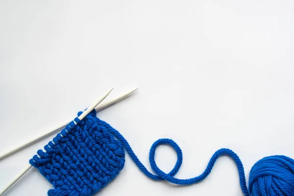 Top view of blue wool yarn and knitting needles on white background — Stock Photo