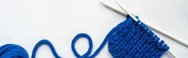 Top view of blue wool yarn and knitting needles on white background, panoramic orientation — Stock Photo