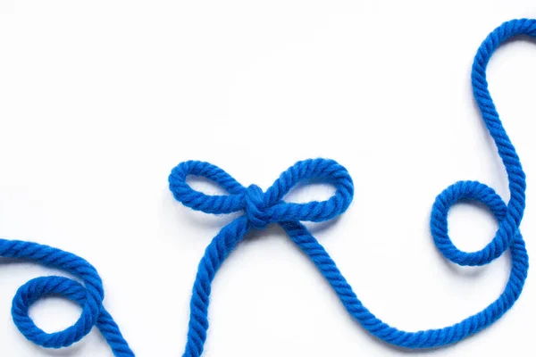 Top view of blue wool thread and bow on white background — Stock Photo