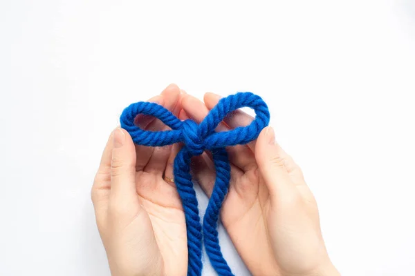 Vista parziale della donna che tiene arco di filo di lana blu su sfondo bianco — Foto stock