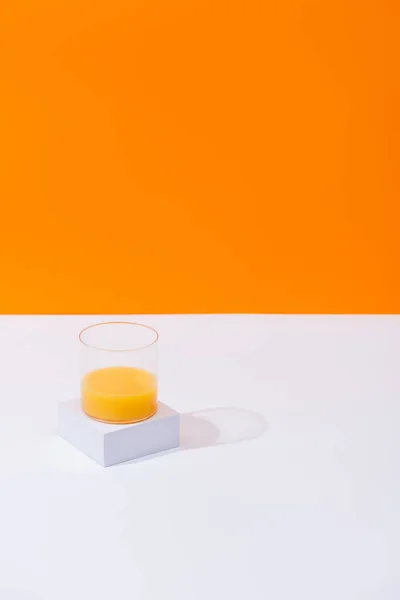 Jus d'orange frais en verre sur surface blanche isolé sur orange — Stock Photo