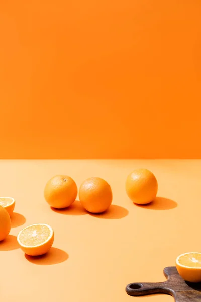 Laranjas frescas maduras e tábua de corte de madeira isolada em laranja — Fotografia de Stock